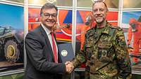 Ein Zivilist und ein Soldat schütteln sich die Hände