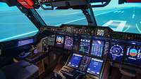 Ein Cockpit des A400M mit vielen Bildschirmen in einem Flugsimulator.