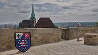 Wappen Landeskommando Thüringen vor einer Mauer. Im Hintergrund Dom und St. Severi Kirche in Erfurt