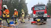 Ein Feuerwehrfahrzeug der Bundeswehr. Mehrere Feuerwehrleute eilen zu einem Unfallort.