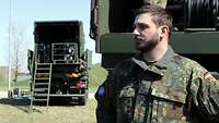 Portrait eines Soldaten, der vor zwei LKWs steht 