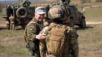 Zwei Soldaten unterhalten sich im Gelände vor Gefechtsfahrzeugen.