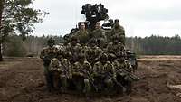 Soldaten posieren für ein Gruppenfoto vor einem Fahrzeug vom Typ Schützenpanzer Combat Vehicle 90.
