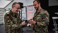 Generalinspekteur der Bundeswehr Carsten Breuer unterhält sich mit einem Soldat über Drohnentechnik