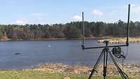 Vor einem See steht eine Antenne mit einem kleinen Display und einer Schaltfläche.