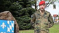 Ein Soldat mit rotem Barett und Bart schaut ernst in die Kamera.