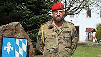 Ein Soldat mit rotem Barett, Brille und Bart schaut freundlich in die Kamera.