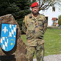 Ein Soldat mit rotem Barett, Brille und Bart schaut freundlich in die Kamera.