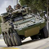 Ein gepanzertes und getarntes fährt auf einer Straße.