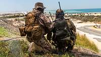 Joint Terminal Attack Controller bei Desert Flag Zwei Soldaten knien nebeneinander auf einem Hügel und schauen in die Ferne