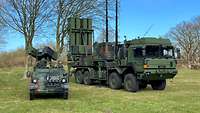 Zwei Militärfahrzeuge stehen auf einer Wiese.