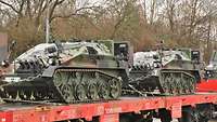Zwei Militärfahrzeuge sind auf einem Transportwaggon der Bahn verzurrt. 