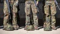 Soldaten sind nebeneinander angetreten uns haben Helme vor sich auf dem Boden liegen.