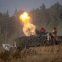 Auf einer Waldlichtung wird von einer grün getarnten Trägerplattform ein Panzermörser abgefeuert.