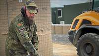 Ein Soldat mit Lärmschutz-Kopfhörern bedient ein lautes und schweres Baugerät.