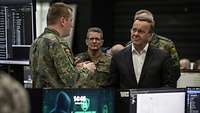 Verteidigungsminister besucht Cyberabwehr-Übung „Locked Shields“ Verteidigungsminister Pistorius steht zwischen Computerarbeitsplätzen und spricht mit einem Soldaten