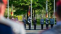 Indienststellung des Unterstützungsbereichs Soldaten stehen angetreten mit drei Truppenfahnen in einer Reihe auf einem Platz