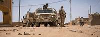 Ein bewaffneter Soldat steht neben Militärfahrzeugen während einer Patrouille in Mali