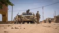 Ein bewaffneter Soldat steht neben Militärfahrzeugen während einer Patrouille in Mali