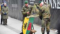 Zwei Soldaten enthüllen ein Wappenschild