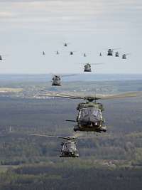 In Formation über Litauen Zahlreiche verschiedene Hubschrauber fliegen in Formation, unter ihnen Landschaft.