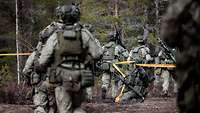 Litauische Infanteristen stürmen durch eine geöffnete Sperre.