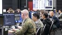 Soldaten verschiedener Nationen sitzen an Computern.