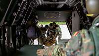Verwundetentransport als gemeinsame Aufgabe Mehrere Soldaten tragen einen Verwundeten in den Hubschrauber. Ein gibt Soldat Anweisungen.