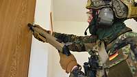 Ein Soldat hält ein Gewehr vom Typ Mehrzweckflinte 5 an eine Tür.