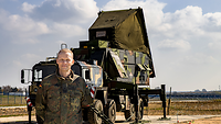 Ein Soldat steht vor einem Militärfahrzeug