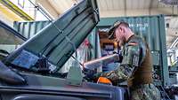 Ein Soldat blick in einen Motorraum eines Bundeswehrfahrzeuges