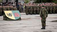 Zahlreiche Soldaten stehen in Formationen angetreten, vor ihnen ein Kommandeur.