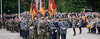 Mehrere Fahnenabordnungen marschieren auf einen öffentlichen Platz ein.