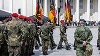 Aufstellungsappell der Panzerbrigade 45 in Vilnius Soldaten marschieren mit Truppenfahnen über einen Platz. Davor stehen Soldaten angetreten.