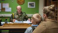 Familienbetreuung Mutter mit ihrem Sohn auf dem Schoß sitzt einem Soldaten gegenüber