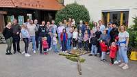 Menschen stehen in einem Hof vor einem Haus