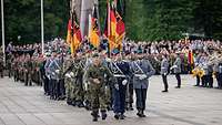 Several flag delegations march into a public square.
