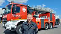 Ein Feuerwehrmann der Bundeswehr steht auf einem Flugplatz vor einem großen roten Fahrzeug