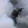 Zwei Soldaten der ukrainischen Armee sind durch Nebel getarnt und bewegen sich auf ein Haus zu.