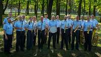 Märkerländer Musikanten des Stabsmusikkorps der Bundeswehr auf grüner Wiese mit Bäumen im Hintergrund