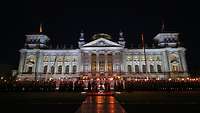 Carrying torches, soldiers march in the dark in front of the Reichstag building in Berlin