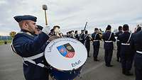 A soldier in a military band plays a drum