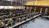 Viele Soldaten sitzen in einer großen Halle an Tischen vor Rechnern.