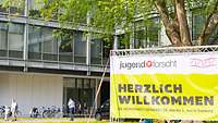 Ein Plakat "Jugend forscht" vor einem Gebäude
