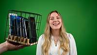 Eine junge Frau vor grünem Hintergrund. Daneben Handys in einem Käfig eingeschlossen.