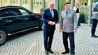 Ein Mann und ein Soldat stehen vor einem Eingangsbereich eines Gebäudes