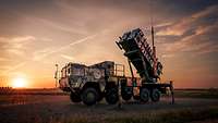 Ein Lastwagen mit Raketenstartvorrichtung und draufgeklebten Tigerstreifen steht im Sonnenaufgang.