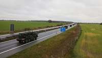 Eine Kolonne militärische Fahrzeuge fährt auf der Autobahn.