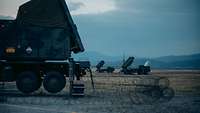 Ein Radar auf LKW steht von Stacheldraht umgeben vor zwei Fahrzeugen mit Raketenstartvorrichtungen.