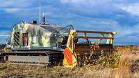 Eine Roboterraupe in polygonem Felcktarn mit einer Art Fräse 